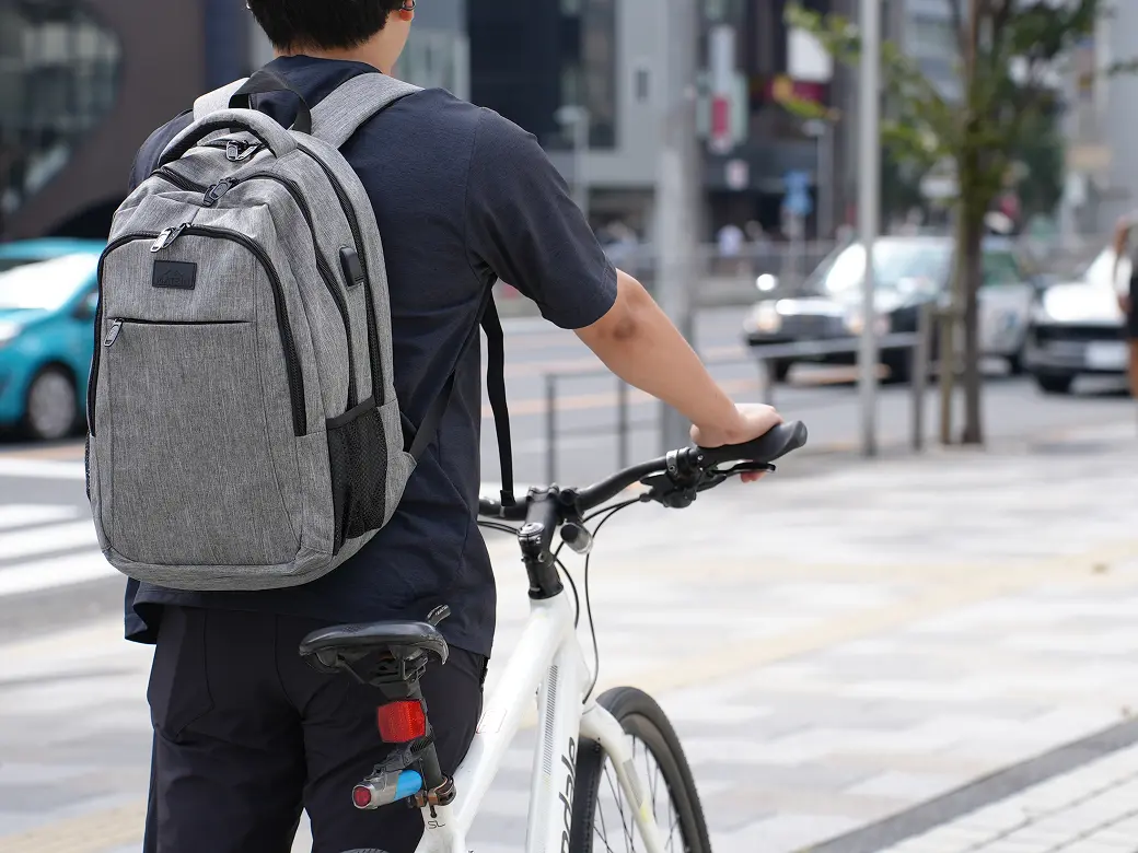 バックパックを背負って自転車に乗る様子
